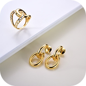 Brincos dourados pequenos com design circular duplo e acabamento polido.